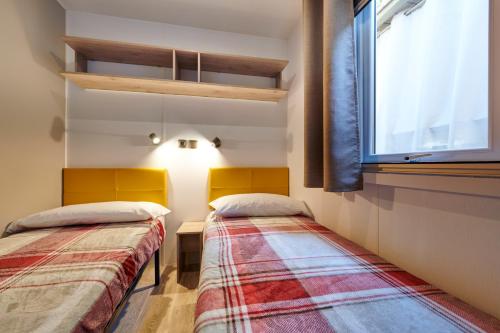 dwa łóżka w pokoju z oknem w obiekcie Campeggio Amici di Lazise w mieście Lazise
