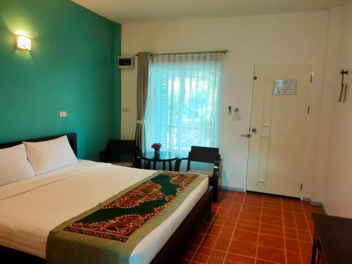 a bedroom with a bed and a window and a door at Baan Jaru in Chiang Rai