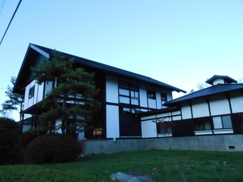 a building with a tree in front of it at Villa Nugget Inn in Omachi