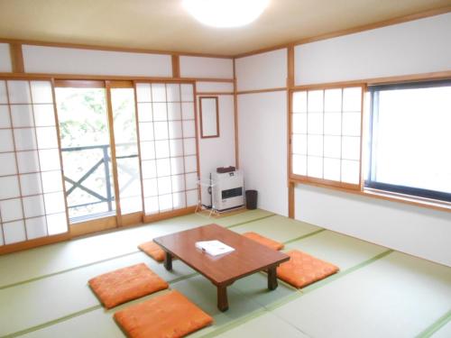 an empty room with a table and orange cushions at Villa Nugget Inn in Omachi