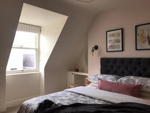 a bedroom with a large bed and a window at Newly renovated seaside townhouse with logburner in Nairn