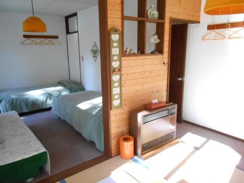 een kamer met 2 bedden en een tv. bij Pension Nugget Inn in Hakuba