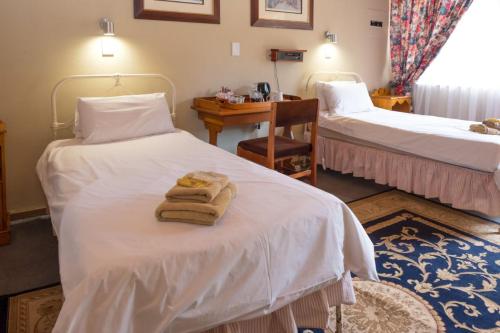 ein Hotelzimmer mit 2 Betten und Handtüchern darauf in der Unterkunft Dullstroom Inn in Dullstroom