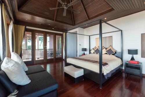 a bedroom with a canopy bed and a couch at Samui Ridgeway Villa - Private Retreat with Panoramic Sea Views in Koh Samui