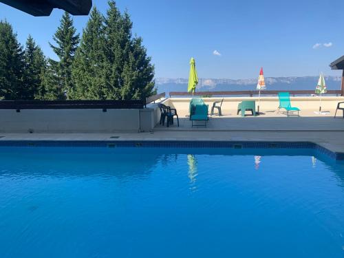 a swimming pool with chairs and umbrellas on a beach at Family apartment on the skiing slope in Allevard