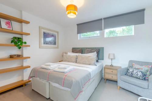 um quarto com uma cama e uma cadeira azul em Cosy 1 Bedroom Apartment near Wimbledon station em Londres