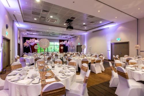a banquet hall with white tables and chairs and purple lighting at Crowne Plaza Birmingham NEC by IHG in Bickenhill