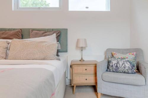 um quarto com uma cama, uma cadeira e um candeeiro em Cosy 1 Bedroom Apartment near Wimbledon station em Londres