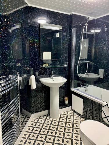 a black and white bathroom with a sink and a shower at Sarum Apart-Hotel in Saint Helier Jersey