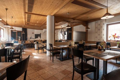 a restaurant with wooden ceilings and tables and chairs at Hotel Mühlenerhof in Campo Tures