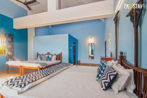 Un dormitorio con dos camas y paredes azules. en EKOSTAY - Cozy Nest Villa, en Karjat