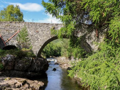 an old stone bridge over a river with a river at Ash in Newtonmore