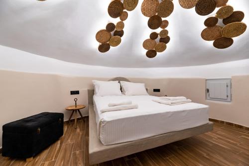 - une chambre avec un lit blanc et une valise noire dans l'établissement Lami Traditional Windmill - With Private pool and Jacuzzi, à Pyrgos