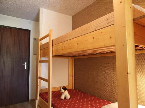 un chien assis au sol sous un lit superposé dans l'établissement Studio avec Balcon Exposé Sud – 4 Couchages, Parking, Chantemerle, Serre-Chevalier - FR-1-330E-108, à Saint-Chaffrey