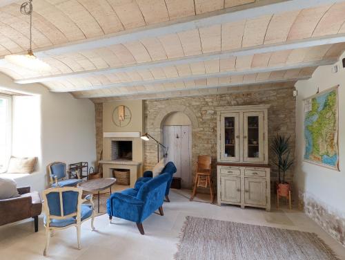 uma sala de estar com cadeiras azuis e uma parede de pedra em Maison typique bretonne avec toit de chaume em Camors