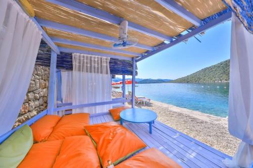 a porch with a couch and a table on the beach at Olympos Mocamp in Kaş