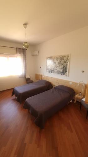 Duas camas num quarto com pisos em madeira e uma janela em Silibardi em Agrigento
