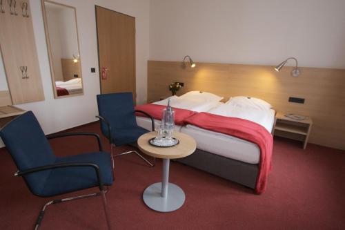 a hotel room with a bed and two chairs and a table at Hotel Haus vom Guten Hirten in Münster