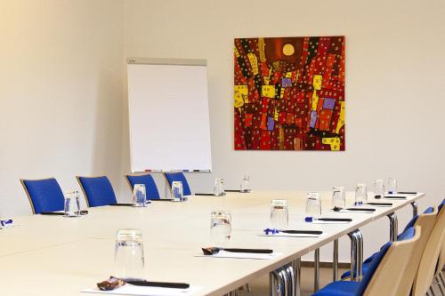 a conference room with a long table and blue chairs at Hotel Haus vom Guten Hirten in Münster