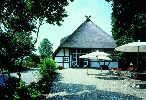 um edifício com telhado de palha e dois guarda-chuvas em Seehotel Am Neuklostersee em Neukloster