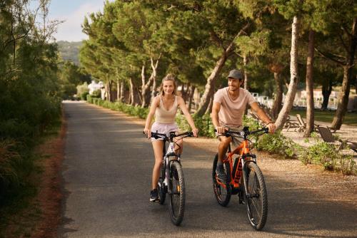 a man and a woman riding bikes down a road at Hotel Laguna - Terme Krka in Strunjan