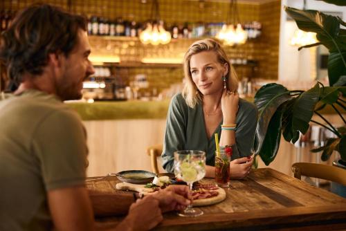 a man and woman sitting at a table eating pizza at Hotel Laguna - Terme Krka in Strunjan