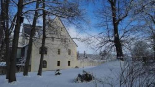 a large white building in the snow with trees at Rittergut Schloss Niederforchheim in Forchheim