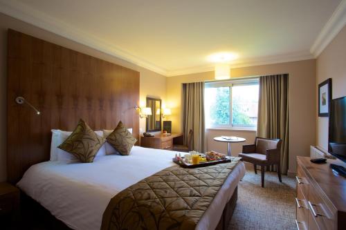 a hotel room with a large bed and a television at Aubrey Park Hotel in Hemel Hempstead