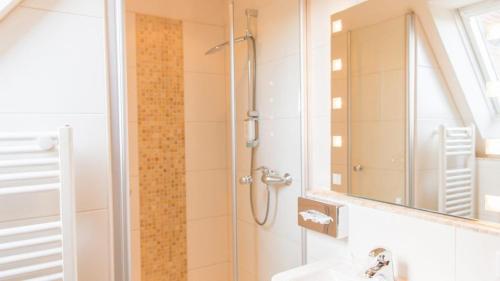 a bathroom with a shower and a sink and a mirror at Meyers Hotel Hittfeld in Seevetal