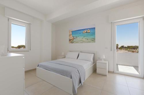um quarto branco com uma cama e 2 janelas em Residence Marelena by BarbarHouse em Casalabate