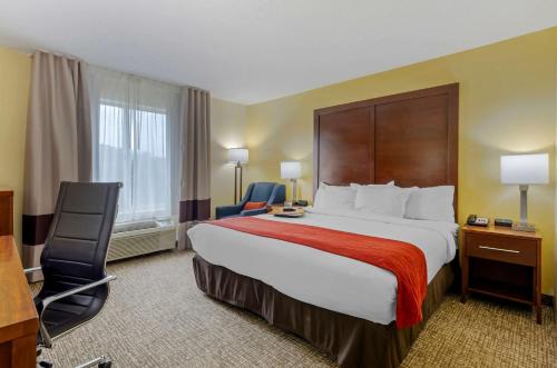 a hotel room with a large bed and a desk and chair at Comfort Inn & Suites Hillsville I-77 in Hillsville
