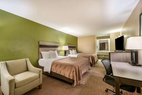 una habitación de hotel con 2 camas y una silla en Quality Inn & Suites - Garland, en Garland
