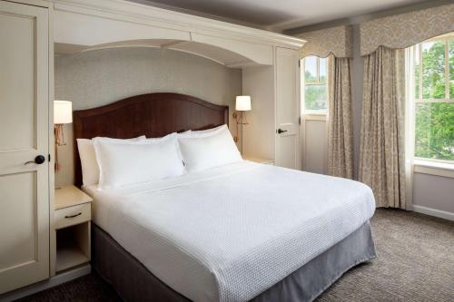 a bedroom with a large bed and two windows at The Elms Hotel & Spa, a Destination by Hyatt Hotel in Excelsior Springs