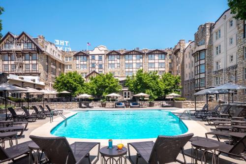 a swimming pool with chairs and tables in front of a building at The Elms Hotel & Spa, a Destination by Hyatt Hotel in Excelsior Springs