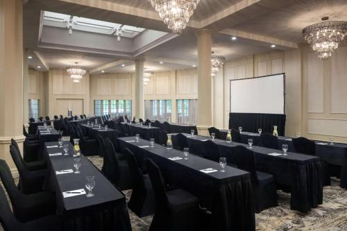 a conference room with tables and chairs and a screen at The Elms Hotel & Spa, a Destination by Hyatt Hotel in Excelsior Springs