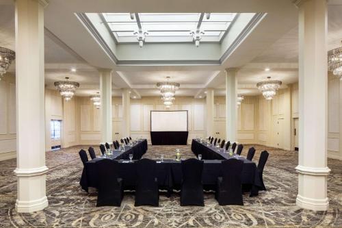 a large banquet hall with black tables and chairs and a screen at The Elms Hotel & Spa, a Destination by Hyatt Hotel in Excelsior Springs