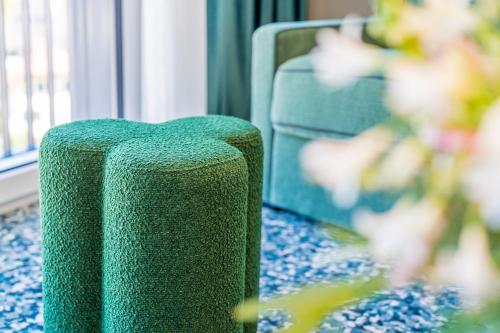 a green chair sitting in front of a window at Hotel D Bulle - La Gruyère in Bulle