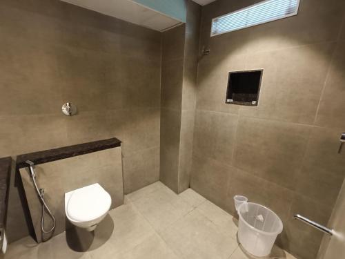 a bathroom with a toilet and a shower with a window at Hotel Comorin Grand in Kanyakumari
