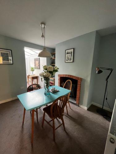 a dining room with a table and chairs and a fireplace at Feather and Twigs Cottage, Croston in Croston