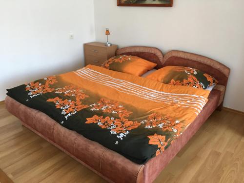 ein Bett mit einer orangefarbenen Decke darüber in der Unterkunft Apartmány Smrečie in Bukovina