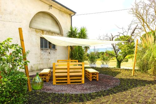a patio with chairs and a white umbrella at Hostly - Il Casale dei Ninì in San Giuliano Terme