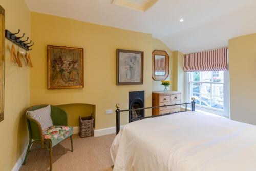 um quarto com uma cama, uma cadeira e uma lareira em Vine Cottage em Charlbury