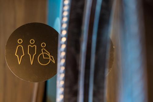 a sign on a wooden door with a toilet symbol at Hotel D Bulle - La Gruyère in Bulle