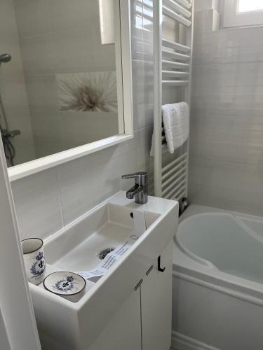 a white bathroom with a sink and a tub at Alma apartments in Suceava
