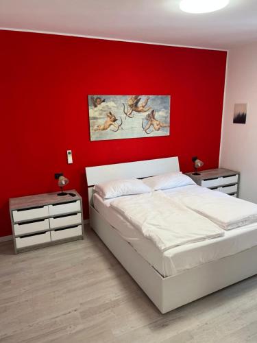een slaapkamer met een rode muur met een bed en twee nachtkastjes bij Apartment Verdi BARDOLINO in Bardolino