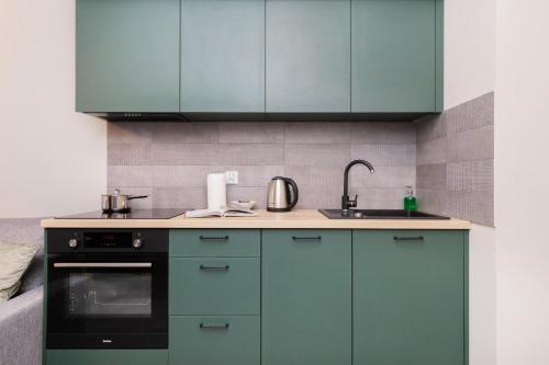 a kitchen with green cabinets and a sink at Modern Studio in Gdańsk, Rybaki Górne by Renters in Gdańsk