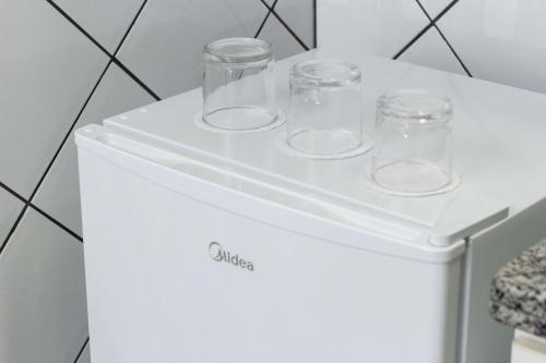 a white refrigerator with four glasses on top at Astor Hotel in Bauru