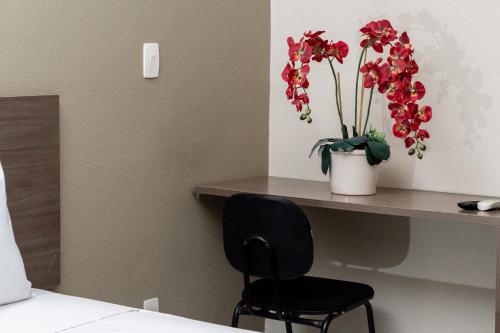a room with a table with a vase of flowers at Astor Hotel in Bauru