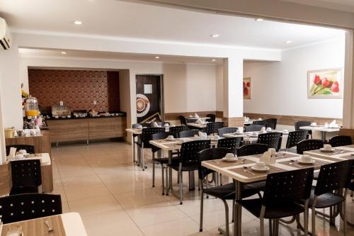 a restaurant with tables and chairs and a counter at Astor Hotel in Bauru