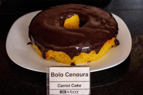 a chocolate covered carrot cake on a plate with a sign at Astor Hotel in Bauru